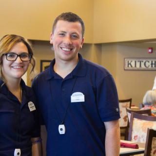 Two employees smiling inside a restaurant.