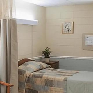 A simple hospital room with a bed, nightstand, and wall decorations.