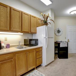 A tidy kitchen with wooden cabinets, a refrigerator, and a microwave on the countertop.