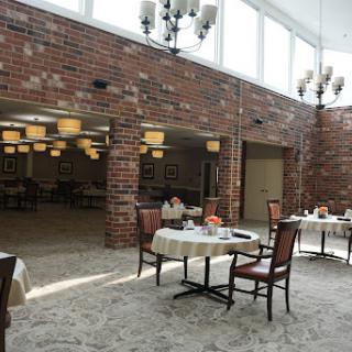 A spacious and inviting dining area featuring elegant chandeliers and a cozy brick wall.