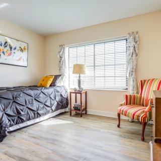 A cozy bedroom with a single bed, striped chair, and a window letting in natural light.