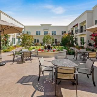 A spacious courtyard with outdoor seating and umbrellas surrounded by a modern building.