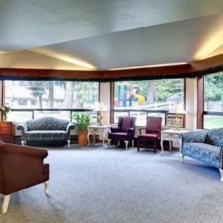 A spacious and well-lit living room with comfortable sofas and chairs, surrounded by large windows.