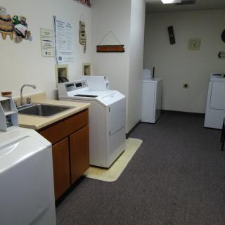 A tidy laundry room featuring multiple washing machines and a sink.
