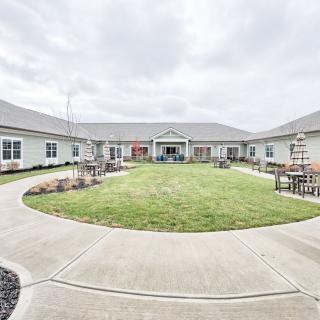 A spacious courtyard with a central lawn, surrounded by a building under an overcast sky.