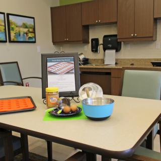 A kitchen table set with baking ingredients, including eggs, peanut butter, and a mixing bowl.