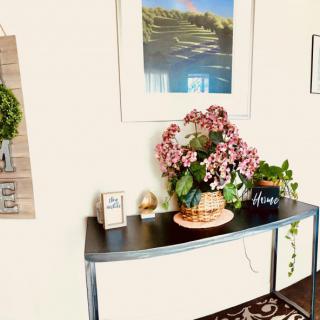 A stylish console table adorned with a vibrant bouquet of flowers and decorative items beneath a framed landscape painting.