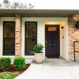A modern house with a brick exterior and a welcoming front entrance, featuring a potted plant and neatly maintained landscaping.