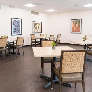 A spacious and modern dining area featuring tables and chairs, adorned with artwork on the walls.