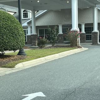 A view of the entrance to a building with landscaped areas and a driveway.