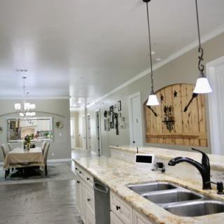 A modern kitchen with a granite countertop and pendant lighting, leading to an open dining area.