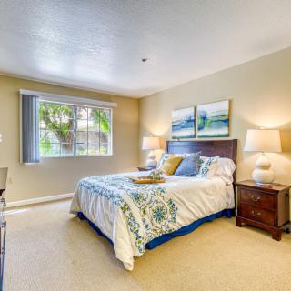 A cozy bedroom with a neatly made bed, bedside tables, and decorative lamps under soft natural light.