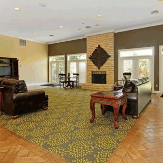 A spacious living room with elegant furniture, featuring a fireplace, large windows, and a patterned carpet.