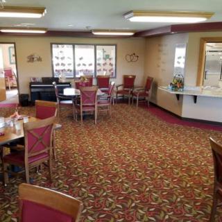 An empty dining room with neatly arranged tables and chairs on a patterned carpet.