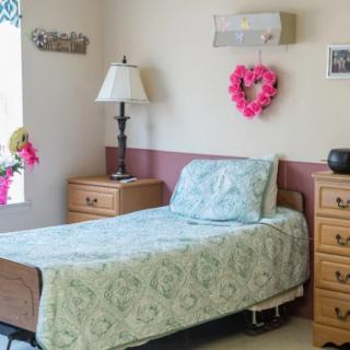 A cozy bedroom with a single bed, lamp, and decorative items.