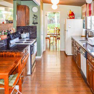 A cozy kitchen featuring wooden cabinets, appliances, and a dining area in the background.