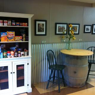 A cozy kitchen corner with a snack cabinet and a barrel table adorned with sunflowers.