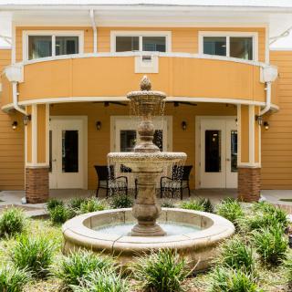 A decorative fountain in front of a modern building with landscaped surroundings.