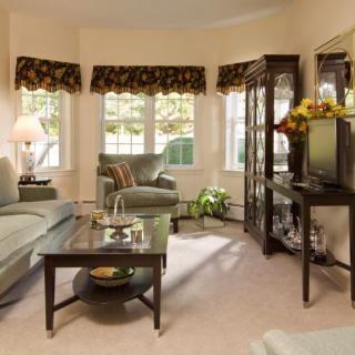 A cozy living room with classic decor, featuring a sofa, armchair, and a TV.
