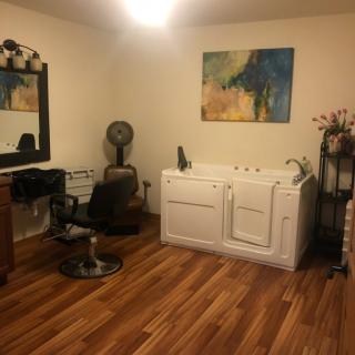 A well-organized salon interior with hairdressing equipment, a chair, mirror, and a bathtub.