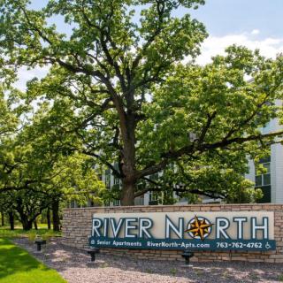 A scenic outdoor view featuring a sign for River North set against a backdrop of lush trees.