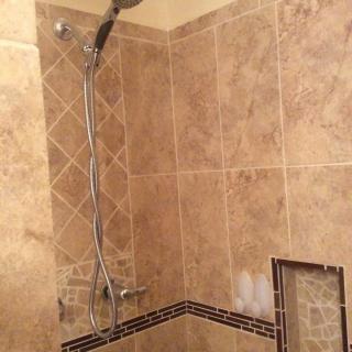 A bathroom shower area with tiled walls and a modern showerhead.