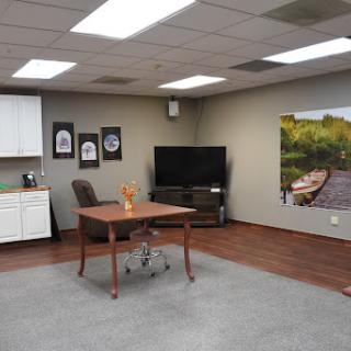 A modern office space featuring a desk, comfortable chair, TV, and decorative art on the walls.