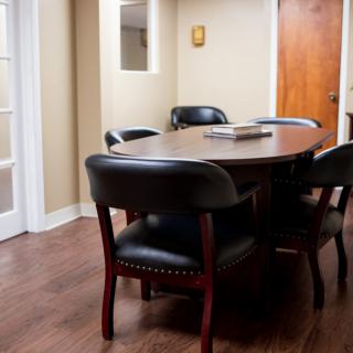 A small conference room with a wooden table and black chairs.