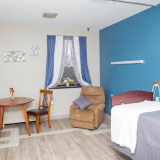 A cozy and modern-looking room featuring a bed, a chair, and a small dining table.