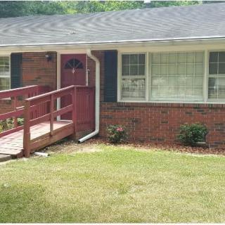 A brick house with a front yard and an accessibility ramp leading to the front door.
