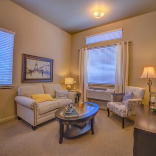 A cozy living room with a sofa, armchair, and coffee table, warmly lit by lamps.