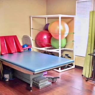 A physical therapy room equipped with exercise balls and a treatment table.