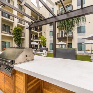 Modern apartment complex patio with a barbecue grill and outdoor seating.