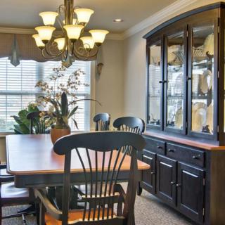 A cozy dining room with a wooden table, chairs, and a large cabinet.