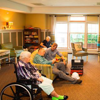 A cozy community room in a nursing home where elderly residents are engaging in conversation and activities.