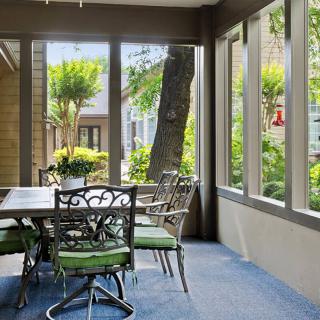 A sunlit dining area with large windows overlooking a garden.