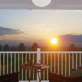 A serene sunset view from a balcony adorned with comfortable chairs and a small table.