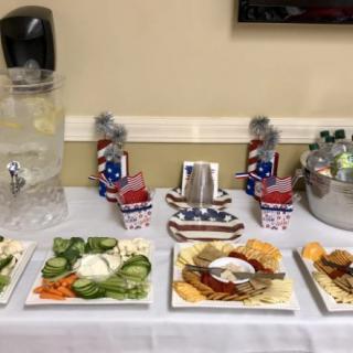 A table set up with a variety of snacks and beverages, featuring patriotic-themed decorations.
