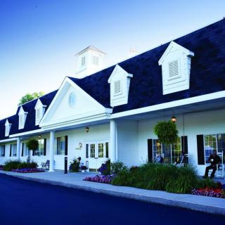 A traditional white building with dormer windows and well-maintained landscaping.