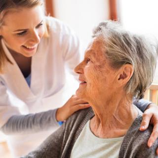 A caregiver provides warm support and companionship to an elderly woman, highlighting the importance of compassionate care in healthcare settings.