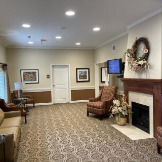 A cozy living room featuring comfortable seating, a fireplace with decorations, and warm lighting.