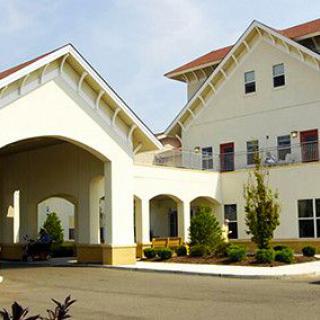 A modern residential building with a covered entrance and landscaped surroundings.