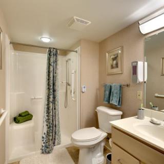 A clean and well-organized bathroom with a shower, toilet, sink, and mirror.