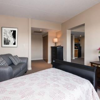 A spacious bedroom with a sofa, bed, lamp, and artwork.