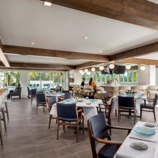 A modern restaurant interior with elegantly set tables and a central bar area.