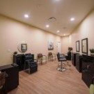 A cozy hair salon interior with chairs, mirrors, and warm lighting.