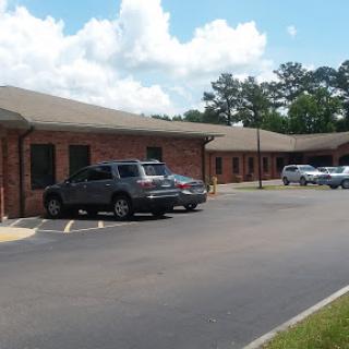 A view of a brick building with parked cars in a sunny, cloudy environment.