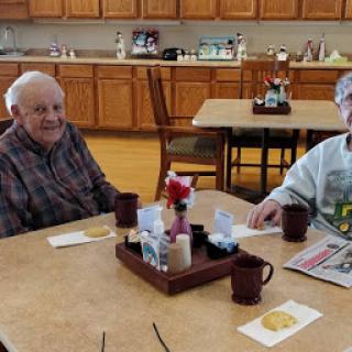 Two elderly friends enjoying breakfast together in a cozy dining area.