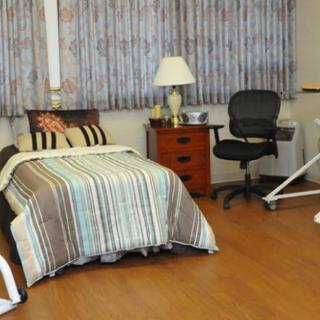 A cozy bedroom with a single bed, striped bedding, and an office chair.