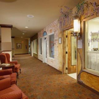 A warmly lit hotel hallway featuring comfortable seating and decorative wall art.